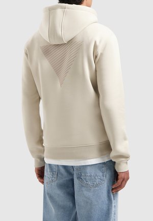 Beige hoodie with a textured triangular design on the back. Features a hood and ribbed cuffs. Worn with light blue jeans.