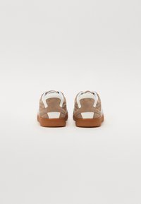 Wildledersneaker mit beigem Obermaterial, weißen Akzenten und einer braunen Gummisohle. Verfügt über ein schlankes Design und einen gepolsterten Kragen für zusätzlichen Komfort.