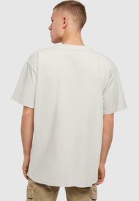 Camiseta de manga corta de color gris claro, hecha de algodón, con un corte relajado y escote redondo, con una textura suave y sin patrones visibles.