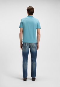 Lyseblå polo t-shirt med korte ærmer og tekstureret stof, parret med tætsiddende blå jeans med lyse nuancer og en let flare ved kanten.