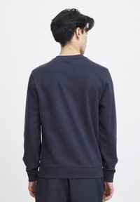 Marineblaue Sweatshirt aus Baumwollmischung, mit Rundhalsausschnitt, langen Ärmeln sowie gerippten Bündchen und Saum. Glatte Textur, minimalistisches Design.