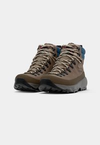 Bottines de randonnée marron avec semelles grises, présentant un extérieur texturé, des lacets beiges et des accents bleus sur le col. Conception durable pour une utilisation en extérieur.