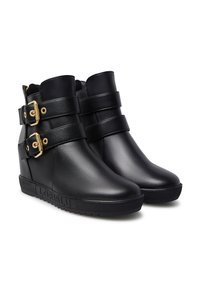 Stivali ankle a zeppa neri in pelle con due cinturini dorati. Texture liscia, punta arrotondata e suola a motivo a canali. Nome del brand "LORIBLU" visibile.