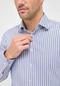 Overhem shirt met blauw en witte verticale strepen, voorzien van een spread collar en een visgraatstructuur. De knopen hebben contrasterende donkere gaten.