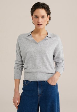 Grå pullovertrøje med V-udskæring og krave, ribstrikkede manchetter og kant, blød tekstur, parret med højtaljede denimjeans.