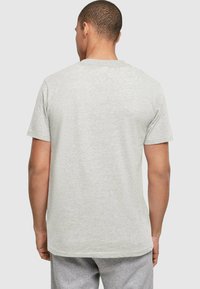 Camiseta gris de manga corta hecha de una tela suave, con un cuello redondo y un ajuste regular. El diseño es simple, sin patrones ni acentos.