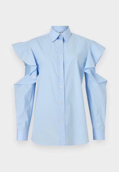 Chemisier bleu clair à boutons, col pointu et manches longues avec épaules découpées et détails à volants.