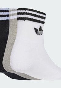 Tri páry členkových ponožiek v čiernej, šedej a bielej farbe; každé má rebrovanú manžetu so tromi pruhmi a vyšívané logo na boku.