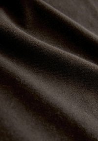 Tessuto marrone scuro con una superficie liscia e testurizzata, che mostra pieghe e grinze sottili tipiche dei materiali tessuti.