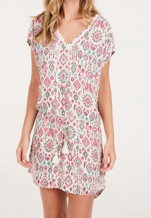 Robe courte avec un décolleté en V, des manches courtes et une taille à nouer. Présente un motif géométrique coloré sur un fond clair. Tissu texturé avec des franges.