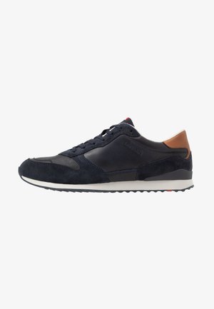 Men's navy sneakers made from leather and suede, featuring a rubber sole, tonal laces, and a brown leather heel accent.