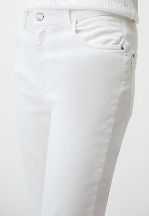 Jeans in denim bianco con una texture liscia, dotati di tasca frontale, chiusura con bottone in argento e dettagli di cucitura laterale.