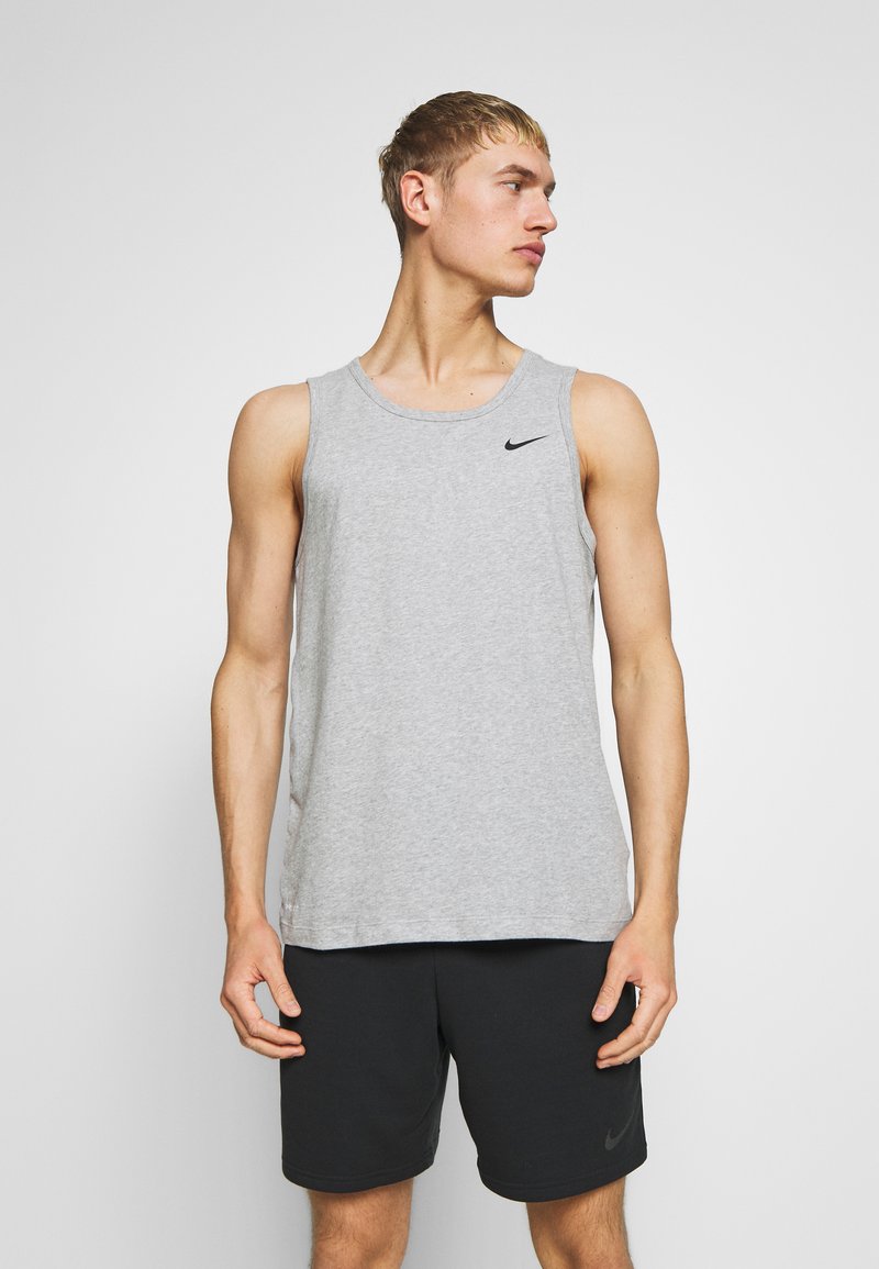Canottiera grigia senza maniche in un morbido cotone misto; presenta un collo rotondo e un piccolo logo Nike nero sul petto. Abbinata a pantaloni corti neri.