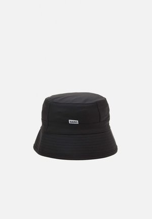 Chapeau seau noir imperméable avec coutures cousues et une petite étiquette blanche du logo Rains à l'avant.