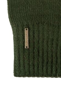 Zöld kötött anyag bordázott textúrával, amelyen egy kis arany fém címke látható, két lyukkal rögzítve.