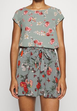 Blomster romper i grøn stof med korte ærmer, en bælte i taljen, der har varierende blomstermønstre i rød, pink og hvid.