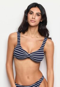 Top de bikini cu dungi bleumarin și alb, cu bretele late și detaliu central legat, realizat dintr-un material texturat. Conceput pentru o potrivire sigură.
