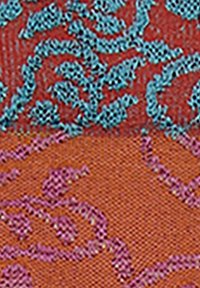 Tessuto con motivi intricati in turchese e viola su uno sfondo rosso textured, che mette in evidenza dettagli tessuti e colori a contrasto.