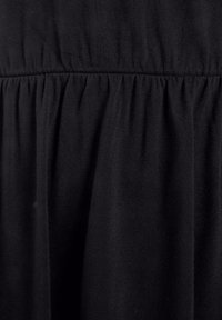 Czarna tkanina o miękkiej strukturze, z marszczeniami wzdłuż szwów, oferująca zwiewny wygląd i gładkie wykończenie.