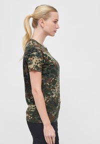 T-skjorte med camo-mønster i grønn, brun og beige. Korte ermer, rund hals, mykt bomullsmateriale, avslappet passform, og detaljert mønster over hele stoffet.