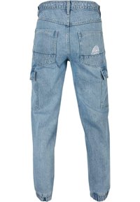 Lysblå denim cargo-bukser med elastiske manchetter, to baglommer og et dekorativt logo på taljen. Har sidelommer.