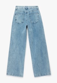 Jeans anchos de color azul claro con textura de denim, bolsillos traseros y adornos de pequeños tachuelas transparentes en el lado exterior.