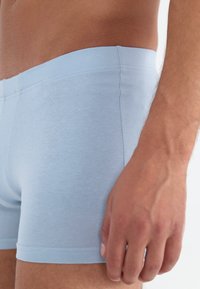 Boxeri din bumbac de culoare albastru deschis, cu o textură netedă, având o croială ajustată și detalii cusute la talie și la deschiderile picioarelor.