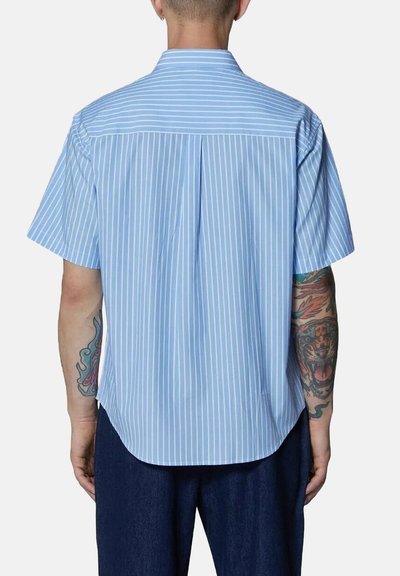Camicia a maniche corte di colore azzurro chiaro con sottili righe bianche verticali, dotata di una spalla posteriore e di un orlo arrotondato.