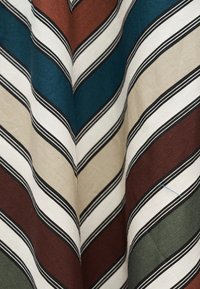 Πτυχώσεις υφάσματος με διαγώνιες ρίγες σε λευκό, μαύρο, καφέ, πράσινο, μπεζ και τιρκουάζ χρώματα δημιουργώντας ένα σχέδιο ψαροκόκκαλο.