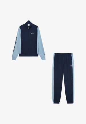 Chándal en tonos azul marino y claro: chaqueta con cremallera y mangas largas con logo, combinada con pantalones ajustados a juego que presentan una cinturilla elástica y rayas laterales.