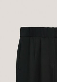 Zwarte broek met een brede tailleband, voorzien van plooien, zijzakken en een gladde stoftextuur. Strakke lijnen en klassiek ontwerp.