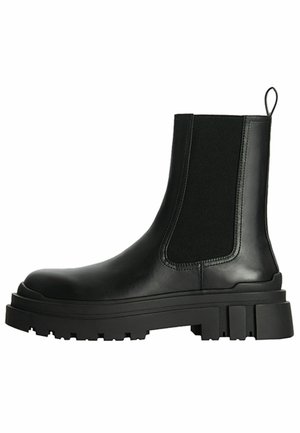 Stivale Chelsea in pelle nera con pannello laterale elastico, suola carrarmato spessa e linguetta posteriore.