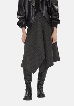 Chaqueta de cuero negra sobre falda midi asimétrica de rayas negras con cinturón ancho en la cintura, combinada con botas negras de cuero hasta la rodilla.