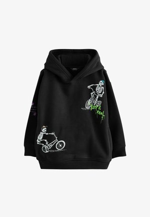 Hanorac negru cu două schelete care merg pe biciclete, unul purtând o pălărie, iar celălalt o căciulă, și text verde care spune "fii autentic" pe față.