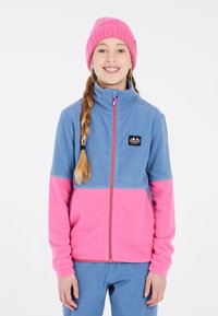 Fleece jack met een blauwe bovenkant en een roze onderkant, voorzien van een rits aan de voorkant en een logo patch. Gecombineerd met een roze gebreide beanie.