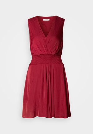 Piros ujjtalan ruha mély V-kivágással, smockolt derékrésszel és lebegő szoknyával. Puha, könnyű anyag, finom textúrával.