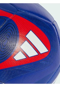 Balón de fútbol de Adidas con paneles azules y rojos, superficie texturizada y un logo blanco prominente con tres rayas.