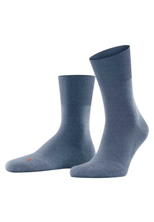 Blaue Baumwollsocken mit einem gerippten Bündchen, glatter Textur und einem roten Akzentpunkt nahe der Zehe. Knöchelhöhe mit einer enganliegenden Form.