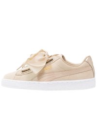 Sneaker beige in suede con suola in gomma bianca, dotato di lacci in raso e un accento in logo dorato. Punta arrotondata e texture liscia.