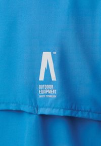 Jasnoniebieska tkanina sprzętu outdoorowego z logo zawierającym literę "A" i napisem „TECHNOLOGIA BEZPIECZEŃSTWA SPRZĘTU OUTDOOROWEGO”. Gładka tekstura.