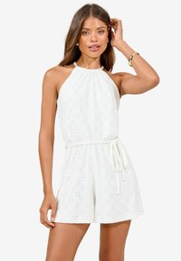 Romper blanc sans manches avec un col halter, une taille cintrée avec un lien et de la broderie œillets sur l'ensemble pour une texture et des détails.