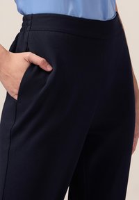 Pantalones azul marino de tela suave, con cintura elástica y bolsillos laterales, que presentan un diseño ajustado que se estrecha hacia el dobladillo.