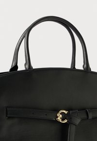 Borsa nera in pelle con forma arrotondata, doppi manici e dettaglio con chiusura in metallo dorato. Texture liscia e design minimalista.