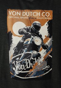 T-shirt noire avec un imprimé graphique d'un motocycliste, agrémenté d'éclaboussures orange et bleues, et du texte "Von Dutch Co." en blanc au-dessus.