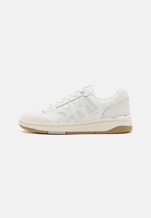 Baskets en cuir blanc avec un design texturé, une semelle beige contrastante et des accents de logo subtils. Silhouette basse classique avec fermeture à lacets.