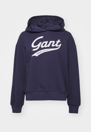 Felpa con cappuccio blu navy in misto cotone, caratterizzata da un grande logo bianco "Gant" e dalla scritta "1949 N.H.C.T." in un design curvo.