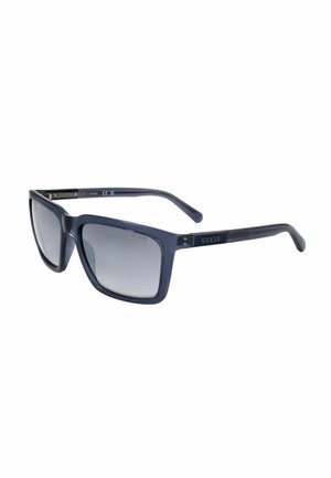 Occhiali da sole rettangolari Guess blu scuro con lenti grigie sfumate e logo sulle aste, mostrati inclinati su sfondo bianco.