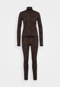 Športový komplet s leopardím vzorom, pozostávajúci z priliehavého, dlhého zipsového topu s dlhým rukávom a zladených legín, oba v tmavých odtieňoch s kontrastnými akcentmi.