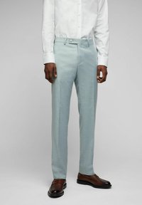 Himmelblaue Hose aus strukturiertem Stoff, mit geradem Schnitt, Gürtelschlaufen und Knopfverschluss, kombiniert mit braunen Dressschuhen.