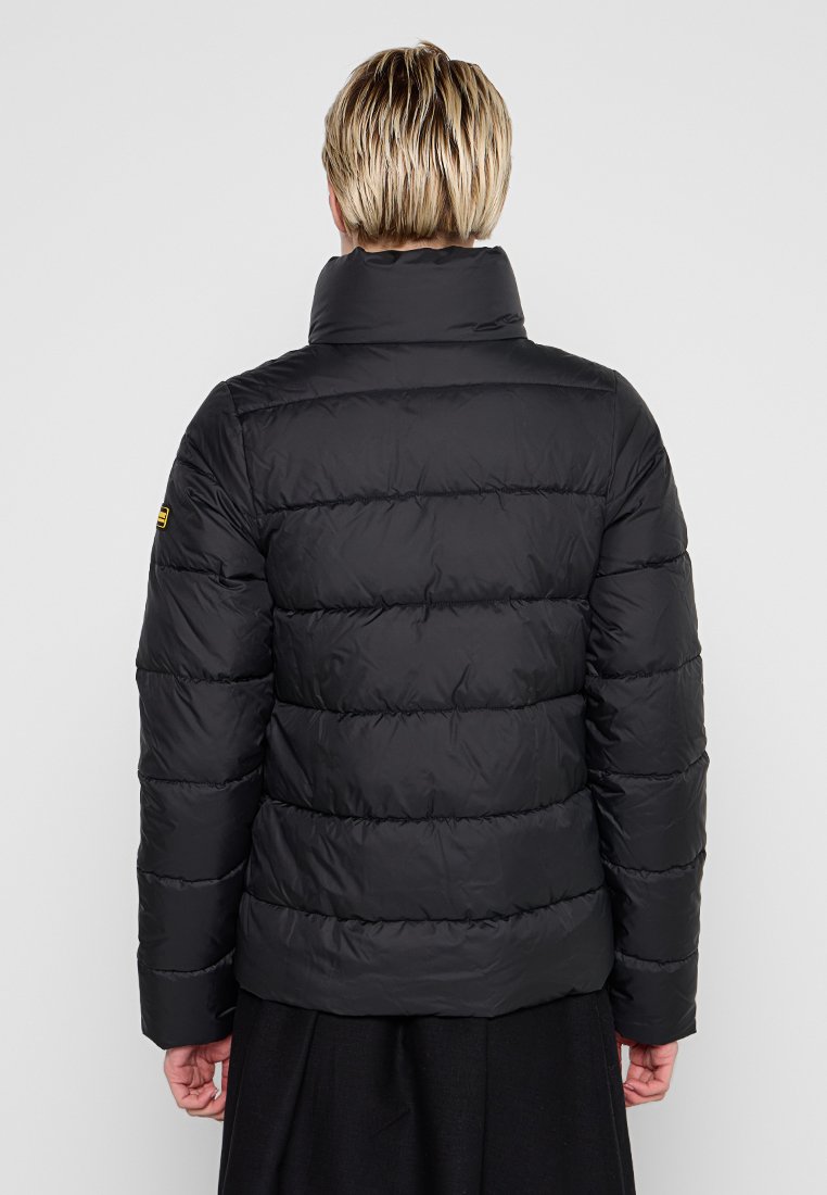 Schwarze Daunenjacke mit einem hohen Kragen und gestepptem Design. Weiche Textur, horizontale Nähte und ein kleines Logo-Detail an der Schulter.